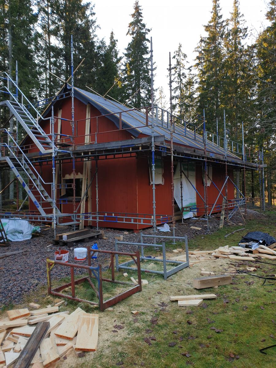 Takarbete med byggnadsställning på röd byggnad